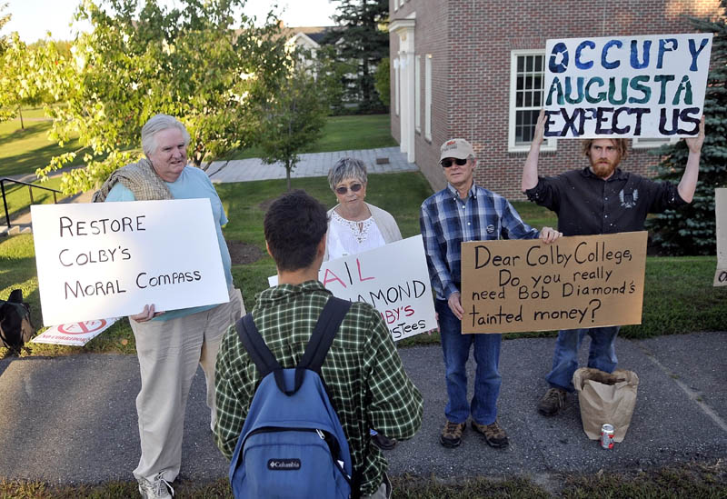 Colby College sophomore Kyle Laurita, foreground, speaks with demonstrators, from left, Bob Shaw, Phyllis Coelho, David Smith and Ed Bonenfant on Wednesday during a protest against the chairman of the college’s Board of Trustees Robert E. Diamond Jr. outside the Diamond building at Colby College on Mayflower Hill Road in Waterville.