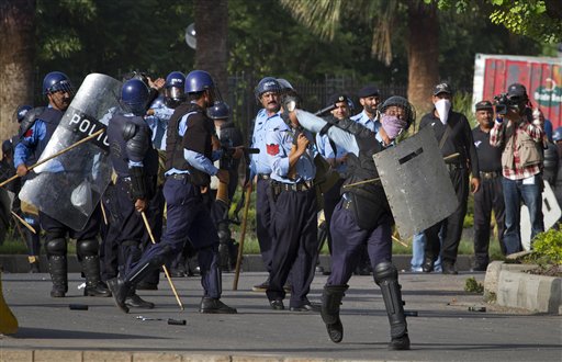 A Pakistani police officer throws a stone as others prepare to fire tear gas at protesters during clashes that erupted near the U.S. Embassy in Islamabad, Pakistan on Friday.