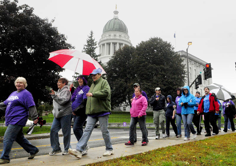 Some of the about 200 participants walk past The State House during the Alzheimer's Association Walk to End Alzheimer's on Saturday morning in Augusta. They walked a 2.8 mile course that started at Buker Center headed down Western Avenue, over to and around Capital Park and back up the Capital Street to the starting point.