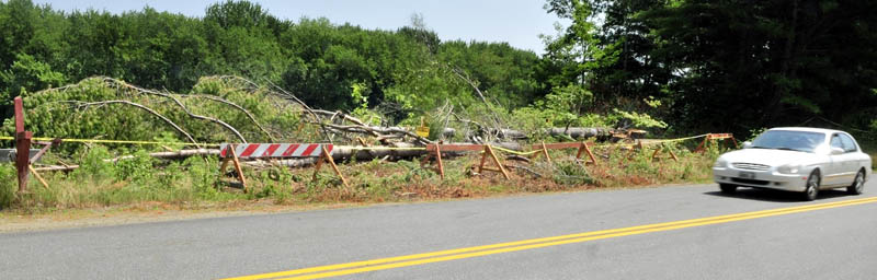 A motorist drives on Whittier Road in Farmington in July past an area where trees have been felled to help slow river bank erosion beside the Sandy River, which flows in background.