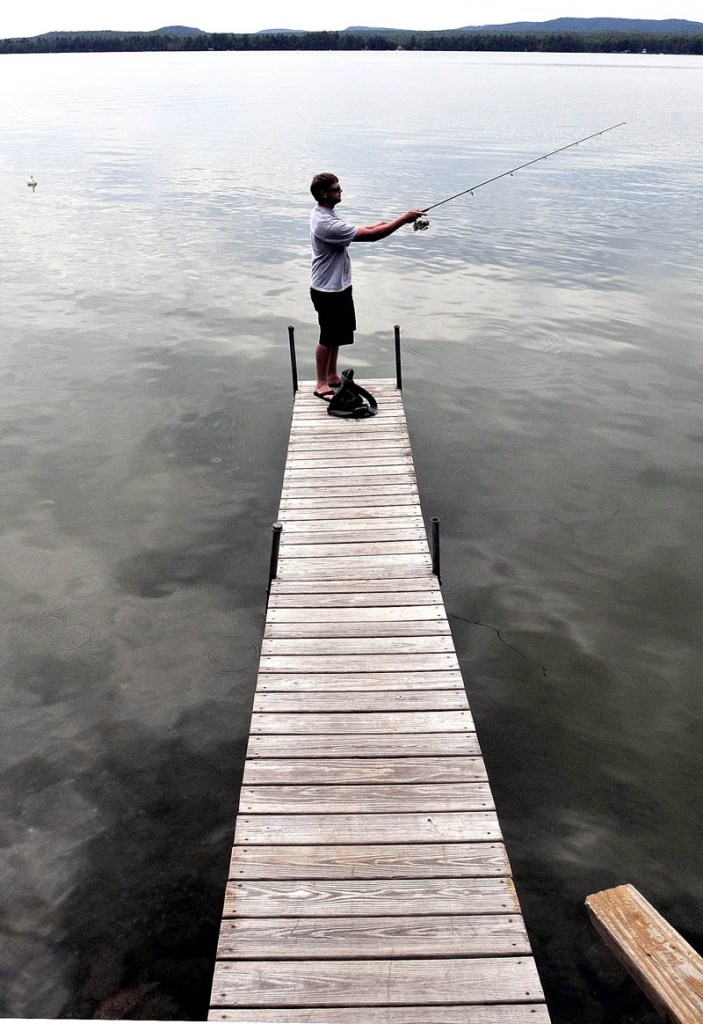 Standing at the end of a long dock, Dan Villwock casts his homemade lure in July 2010 while fishing for bass in North Pond in Smithfield, which is a part of the Belgrade Lakes Watershed.