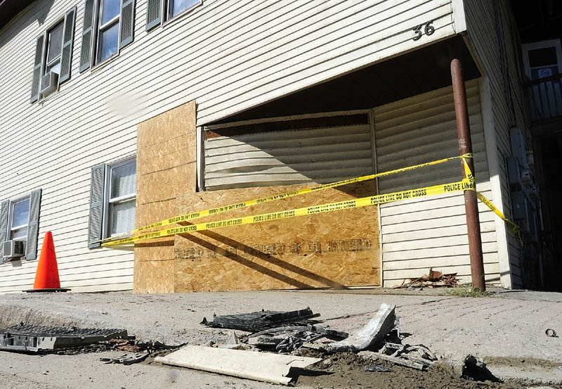 Plywood covers a hole in the wall on Saturday of 36 Water Street where a vehicle drove into Jim Pinkham's apartment on Friday evening. The orange cone, at left, covers the base of where a streetlight used to stand. Bits of streetlight and the vehicle are still on curb.