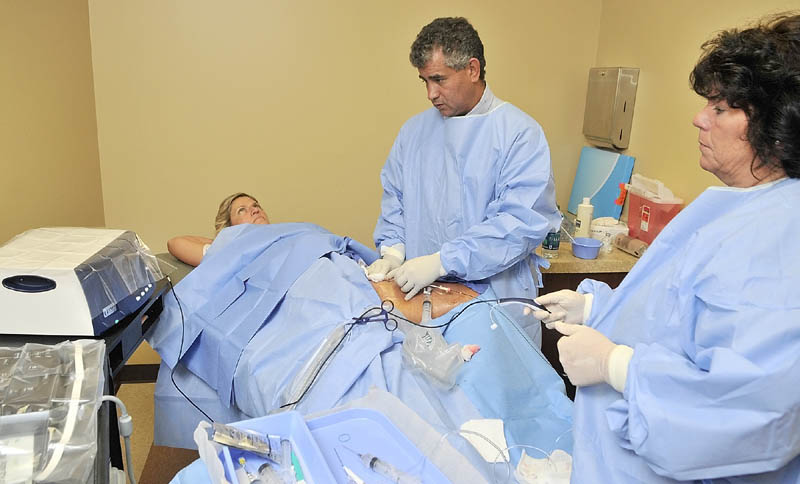 Dr. Chris Alvarado, center, and nurse Kim Gallant, right, perform a Venefit procedure on Vickie Hunnewell to treat chronic venous insufficiency recently in Manchester.