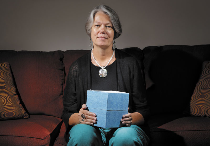 Karin Anderson holds a box of the cremated remains of her husband Steve, who passed away two and a half years ago. Anderson is photographed in her Portland apartment on Thursday.