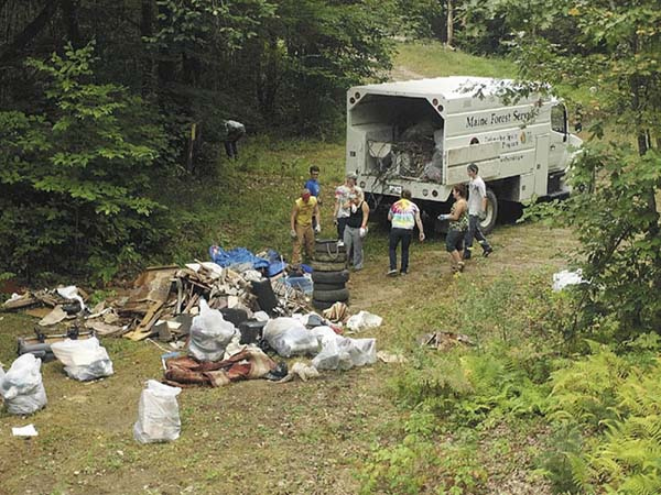A group of young men and women pick up trash Saturday at an illegal dump site off Chesterville Ridge Road in Fayette. A group of roughly 20 teens and young adults, all of whom were charged in connection with an underage drinking party last month in Wayne, took part in the first ever Landowner Appreciation Clean-up Day. The group spent eight hours picking up trash in Fayette and Augusta in lieu of appearing in court. All of those pictured are 18 or older.