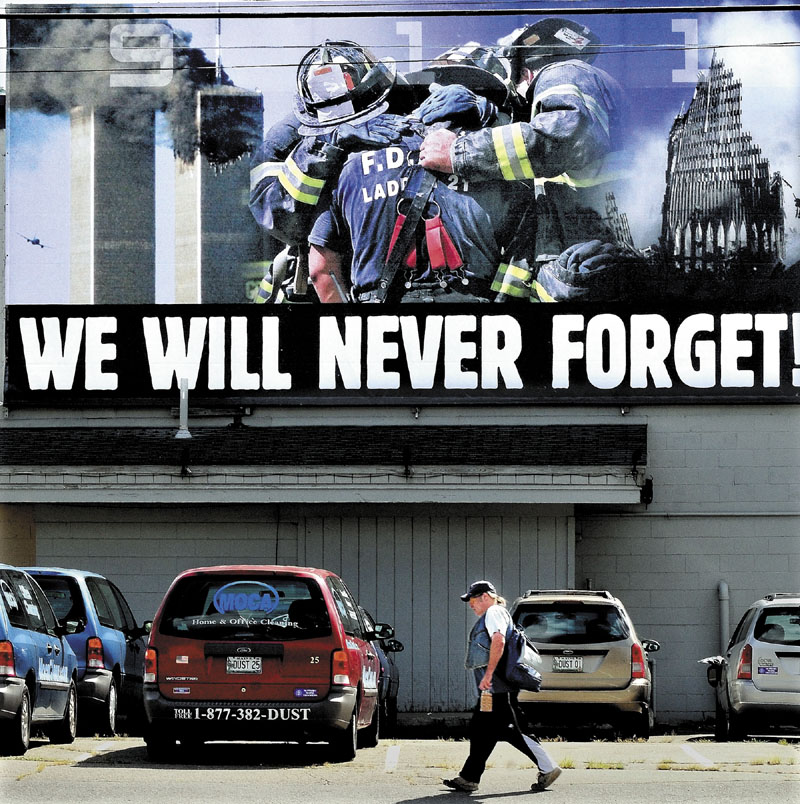 A pedestrian walks under a large mural in Waterville of firefighters embracing as the Twin Towers collapse in New York after terrorists attacked on Sept. 11, 2001.