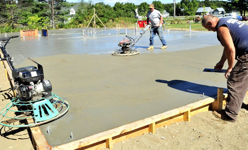 FOUNDATION: Dan Ellis, left, and Larry Hotham of Hotham concrete smooth the new foundation that was poured on Wednesday for the New Hope Women's Shelter in Solon.