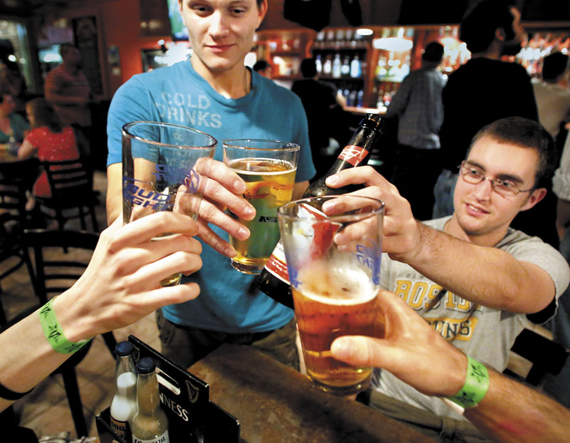 Joseph Miller, a senior ecology and environmental science major from Topsham, left, and Andy Bepuain, a senior business managment major from Bangor, toast with friends at the Bear Brew Pub in Orono.