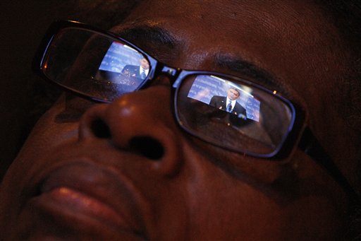 President Obama is reflected in Mary Jackson's eyeglasses as she watches the first Presidential debate between Republican presidential candidate, former Massachusetts Gov. Mitt Romney, and President Barack Obama on Wednesday Oct. 3, 2012, at a restaurant in the West Oak Lane section of Philadelphia. (AP Photo/ Joseph Kaczmarek)