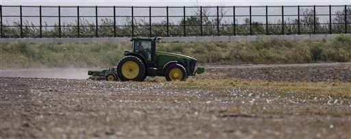A tractor works a cotton field along the border fence that passes through the property in Brownsville, Texas.