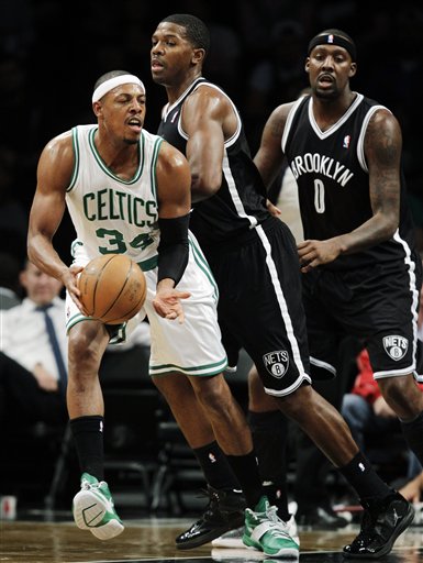 Boston Celtics forward Paul Pierce (34) passes the ball as Brooklyn Nets guard Joe Johnson (7) and forward Andray Blatche (0) defend in the first half of their preseason NBA basketball game at Barclays Center, Thursday, Oct. 18, 2012, in New York. (AP Photo/Kathy Willens)