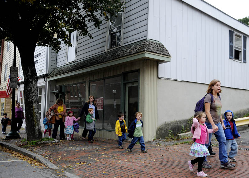 Children walk by 318 Water Street in Gardiner on Wednesday that is available for free for a business to occupy during the months of November and December.