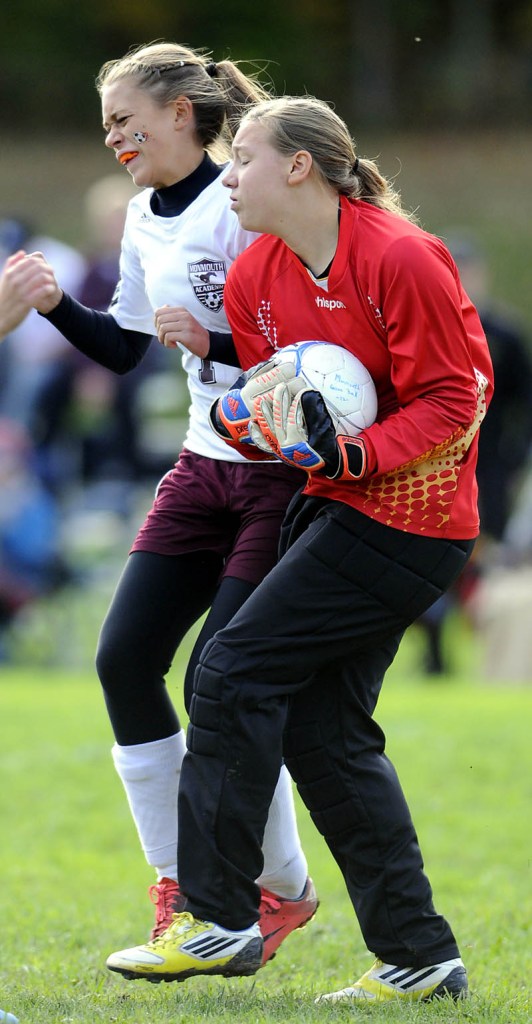 Hall-Dale High School’s goalkeeper Olivia Maynard, right, holds onto the ball under pressure from Monmouth Academy’s Paxton Lessard during a game Monday in Monmouth. Kylie Kemp had a goal and three assists and DAnielle Bumann added two goals as the Mustangs won 4-1. For local roundup, see C3.