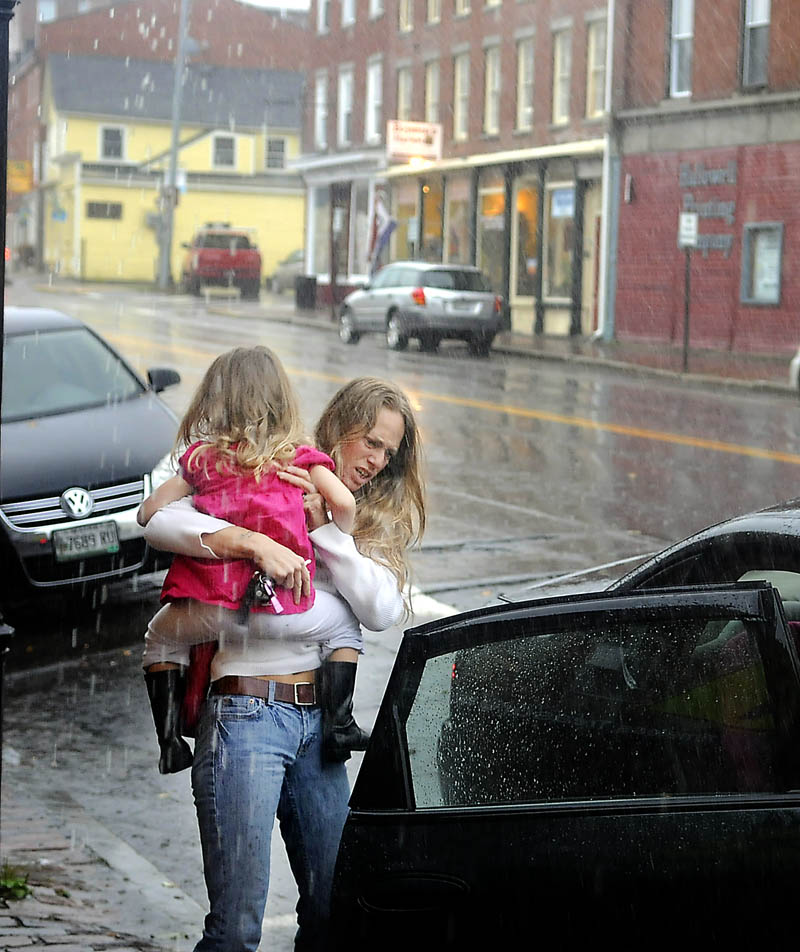 Dawn Lebourdais, of Gardiner, carries her daughter, Sivanna, 4, through a downpour Tuesday in Hallowell. Several inches of rain fell throughout Maine from remnants of superstorm Sandy.
