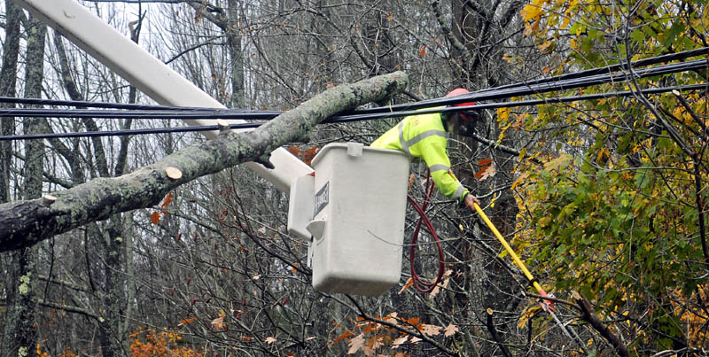 Lucas Tree employee Donny Tunison clears a limb from power lines Tuesday in Hallowell. Tunison and his colleague, Caleb Taylor, removed fallen trees as Central Maine Power crews restored power.