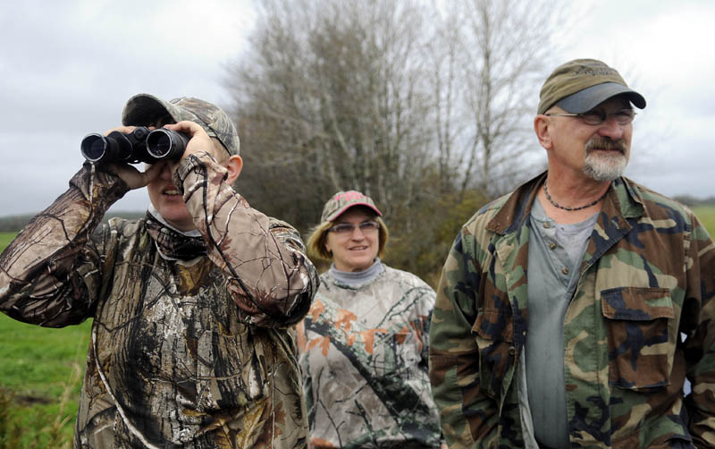 COVERT: Felicia Bell, left, of Richmond, Louis Chase and her husband, Rodney, of Bryant Pond, scan a field Monday for wild turkeys in Richmond. The Chases were accompanying Bell on her first hunt for tom gobblers grazing in open spaces in Richmond. The fall turkey season opened Oct. 13 and concludes Oct. 19.