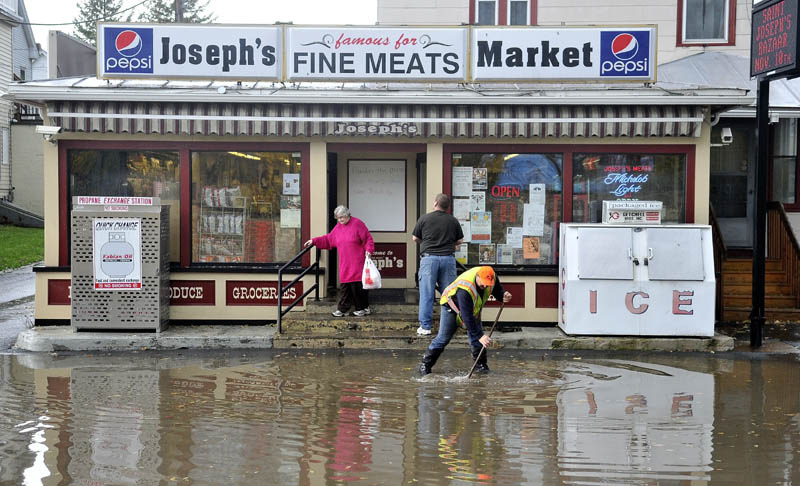 Dave Vigue of the Waterville public works department clears a clogged drain on a flooded Front Street, in front of Joseph's Market, in Waterville after heavy rain on Tuesday.