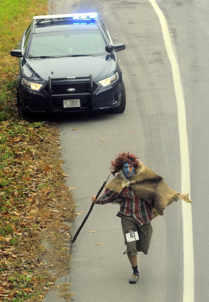 Staff photo by Michael G. Seamans David Gulak, dressed as William Wallace from Braveheart, runs up Mayflower Hill Drive as a Waterville police car watches traffic during the 4th annual Freaky 5k Run and Walk hosted by Hardy Girls Healthy Women and the Colby Volunteer Center at Colby College Saturday morning.