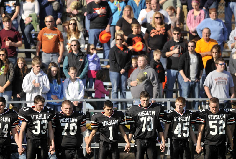 The Winslow High School football team holds hands during a moment of silence on Saturday, for two classmates killed in a car accident late Friday night.