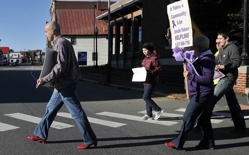Jon Heath, left, leads the 2nd annual Walk A Mile In Her Shoes march in a pair of red heels across Water Street in downtown Skowhegan Saturday morning. The march was organized to help raise awareness of domestic violence in Somerset County.