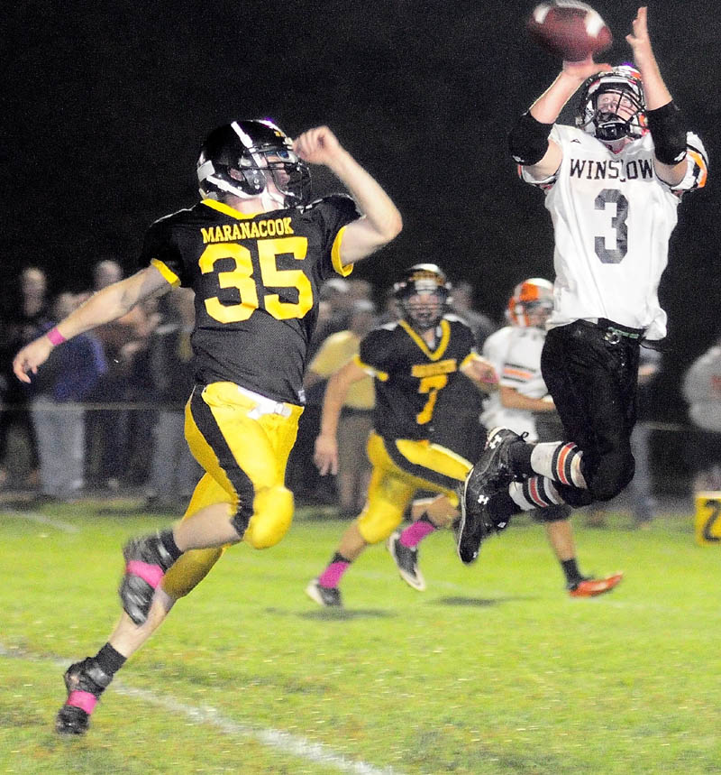 Staff photo by Joe Phelan Maranacook linebacker Logan Emery, left, can't stop Winslow running back Dylan Hapworth from catching a long pass during a game Friday night at the Ricky Gibson Field of Dreams in Readfield.