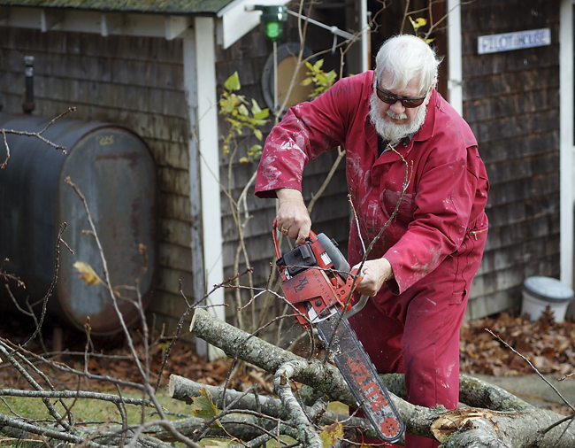 Bill Gribbin, 72, of Littlejohn Island, Yarmouth, cuts up a large tree limb that had fallen into his yard during the storm.