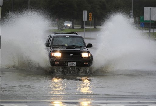 A car plows through a flooded street as rain and wind from Hurrican Sandy hit Norfolk, Va., on Sunday.