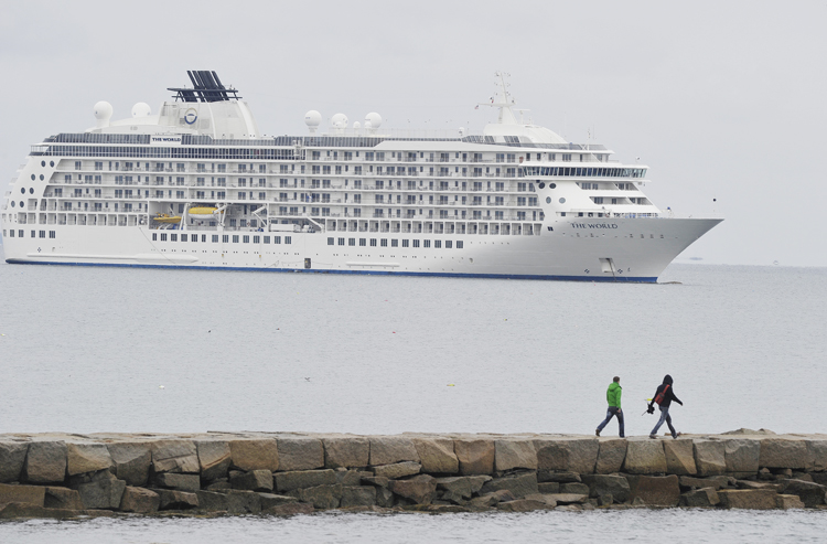 Two hikers walk along the causeway to Rockland Breakwater Light to get a closer look at the 644-foot, privately owned condominium ship The World.