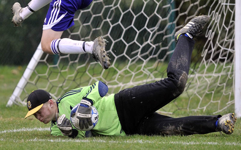 Staff photo by Michael G. Seamans Erskine Academy goalie Jared Gartley, makes a save as Waterville Senior High School's Michael Oliveira, 4, tries to get the rebound in the second half at webber Field in Waterville Friday afternoon. Waterville defeated Erskine 4-0.