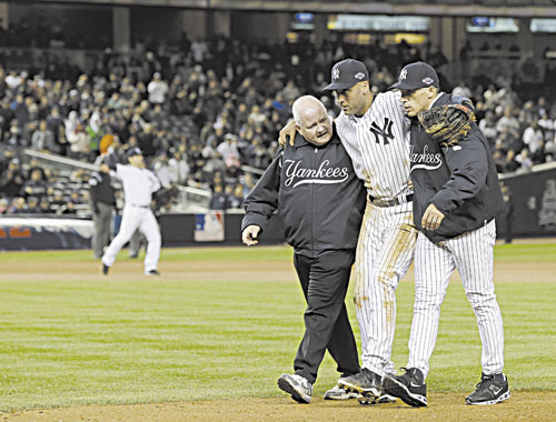 OUCH: Trainer Steve Donohue, left, and New York Yankees manager Joe Girardi, right, help Derek Jeter off the field after he broke his left ankle during Game 1 of the American League Championship Series against the Detroit Tigers early Sunday morning in New York.