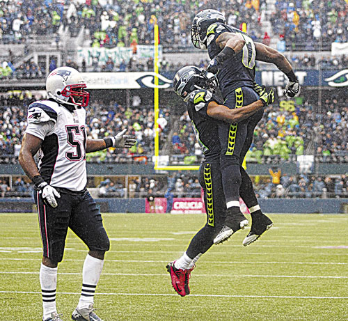 JUMP FOR JOY: Seattle’s Braylon Edwards, right, celebrates with teammateGolden Tate as New England’s Jerod Mayo looks on after Edwards caught a pass for a touchdown in the second half Sunday in Seattle.