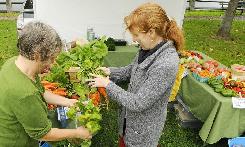 Laura Whatley, of Whatley Farm in Topsham, left, holds a bag open for customer Selma Holden, of Hallowell, to load up with golden beets on Wednesday afternoon at the Gardiner Farmers Market Wednesday afternoon on the Gardiner Common. The market is held there every Wednesday from 2 to 6 p.m.