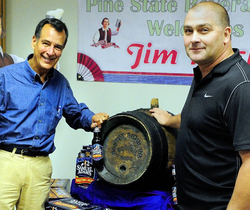 Jeff Damon, co-owner of Damon's Beverage Mart, right, donated this antique wooden beer keg to Jim Koch, left, founder of the Boston Beer Company and the maker of Samuel Adams beers.