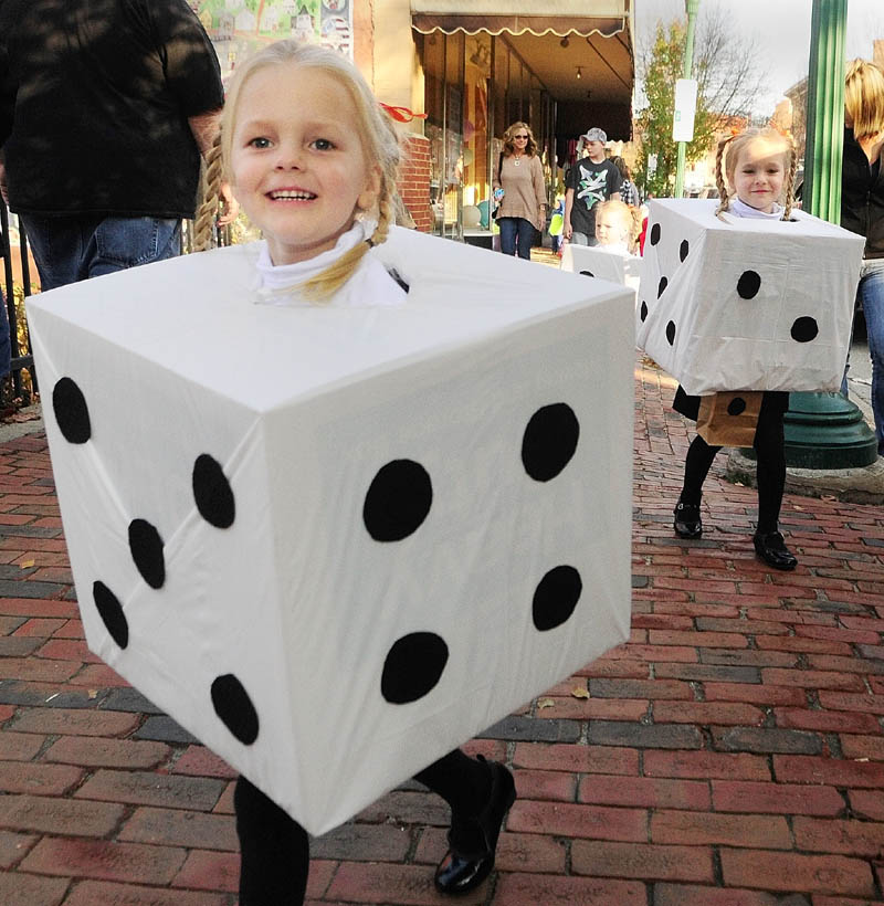 YAHTZEE: Hallee McCarthy, 3, left, leads her sisters Chloe, 4, right, and Taylor, 3 center, as the three girls from West Gardiner, walk down Water Street on Friday afternoon in downtown Gardiner. Hundreds of people were trick or treating at businesses on the street before a parade and costume were held.