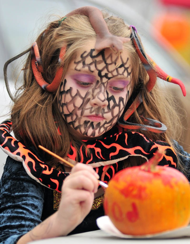Staff photo by Joe Phelan Sedona Kmen paints a pumpkin during Halloween events on Wednesday afternoon at the Gardiner Farmers Market on the Common. Besides the the usual market stalls, there were face painting and games for the holiday.