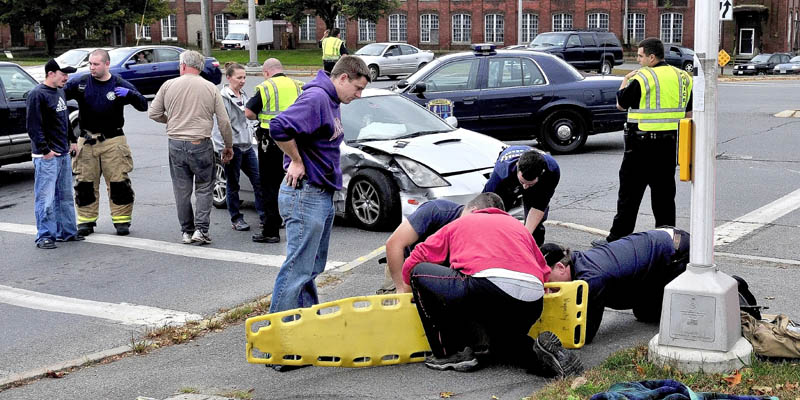 Waterville police and ambulance personel treat injured following an accident at the intersection of Main and Spring Streets in Waterville on Monday.