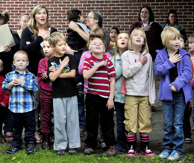 Staff photo by David Leaming CHARTER SALUTE: Children salute the American flag that was raised for the last time before being retired during the opening of the new Cornville Regional Charter School on Monday.