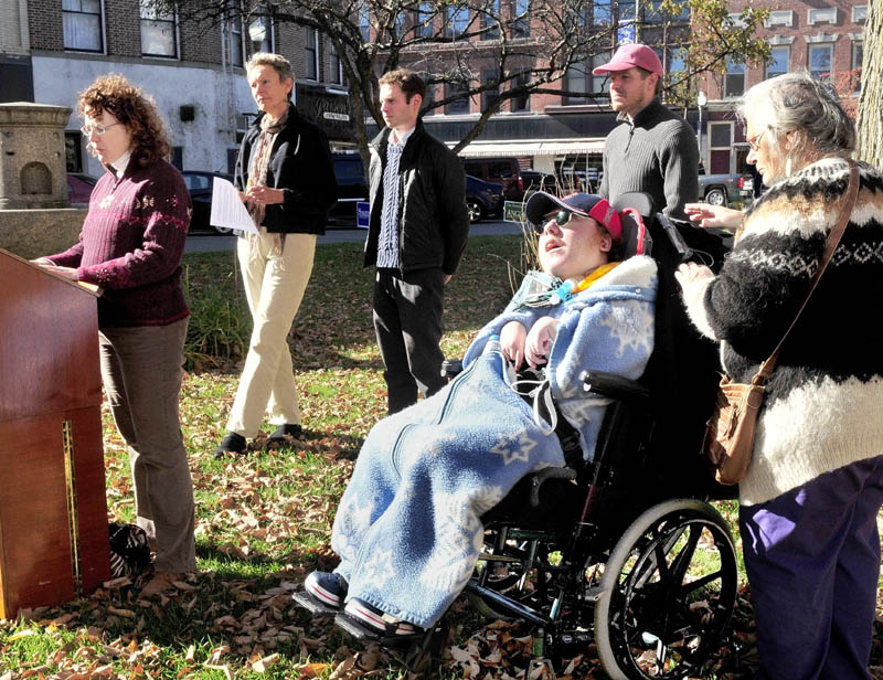 Deborah Klane of Fairfield speaks about the impact of rising health care costs for small business owners as health care provider Ellie Symonevich attends to Klane's disabled son Evan, during a rally in Waterville on Wednesday. Behind Klane is Waterville Mayor Karen Heck, Jonathon Hillier and Erik Thomas.