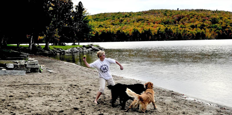 Staff photo by David Leaming Lori White of Skowhegan throws balls for her dogs at the beach and picnic area at Lake George Regional Park East in Canaan.