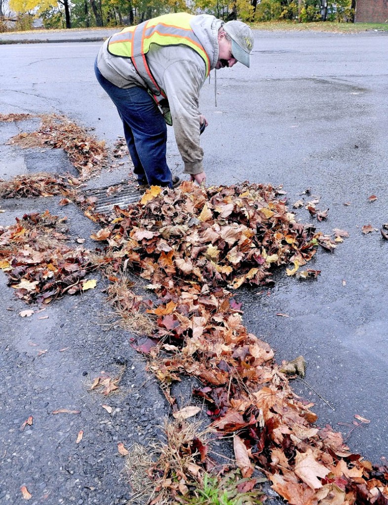 STORM PREP: David Vigue of the Waterville Public Works department on Monday clears a drain full of leaves on Spruce Street ahead of the wind and rain expected from Hurricane Sandy. "Our chainsaws are all gassed up to use for the next few days," Vigue said.