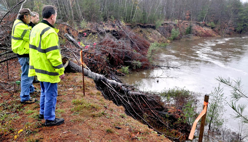 Farmington fire chief Terry Bell, in back, Public Works Director Denis Castonguay, left, and Franklin County Emergency Management Director Tim Hardy monitor the rising Sandy River in Farmington on Tuesday, at the site of erosion of a steep bank beside the Whittier Road.