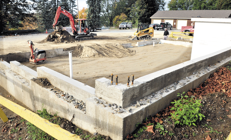 Rick Labbe Construction workers spread gravel for a foundation base outside the Winslow Police department renovation project on Tuesday.