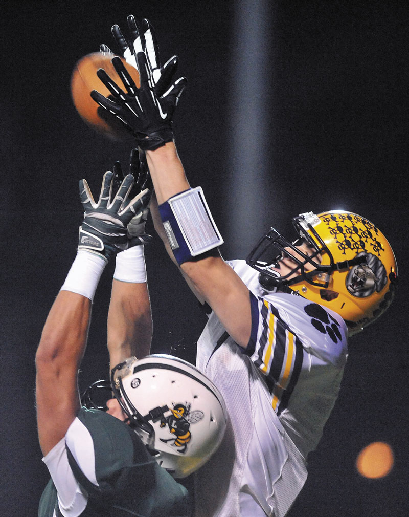 UP AND OVER: Mt. Blue High School receiver Cam Abbott, right, reaches over Leavitt High School defender Brian Bedard for a touchdown on the second play in the first quarter Friday at Leavitt High School in Turner.