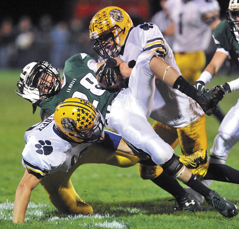 Leavitt High School's Josh Faunce, center, is sandwiched by Mt. Blue High School defenders Jordan Whitney, bottom, and Brian Durrell, top, in the second quarter at Leavitt High School in Turner Friday night. Mt. Blue lead at halftime 20-6.
