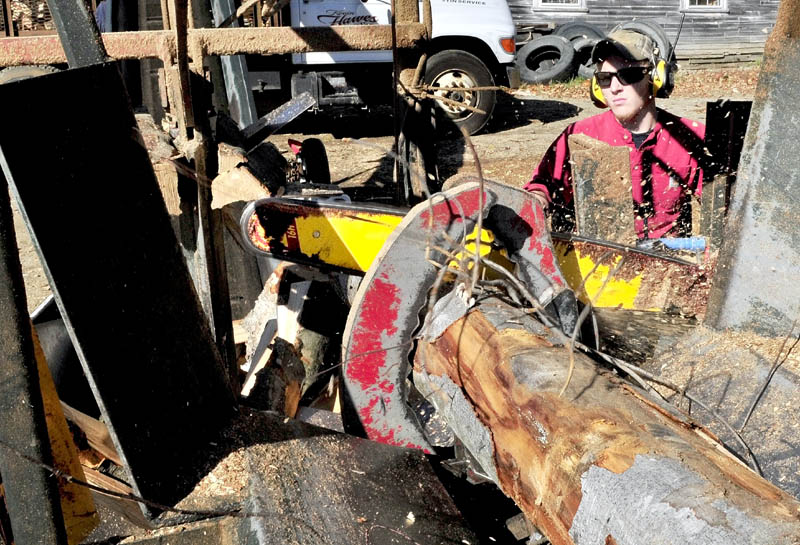 Jesse Bedard operates a firewood processor as a saw blade cuts through a full length log at Hawes & Son Logging and Excavation in Belgrade on Wednesday. After the wood is cut it is automatically split before a conveyor belt loads it into a delivery truck.