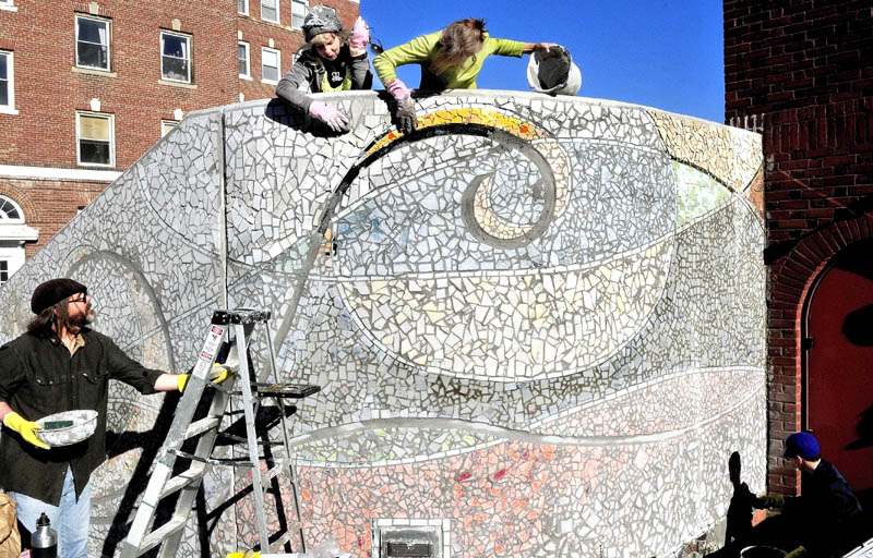 Artists Jane Burke, left, and Gina Colombatto rub off grout from the nearly complete mosaic "Oh! Courant" on the stairs of the Waterville Public Library on Thursday. Michael Libby and Victoria Stubbert also work on each side. The art will be covered before being officially unveiled in November.