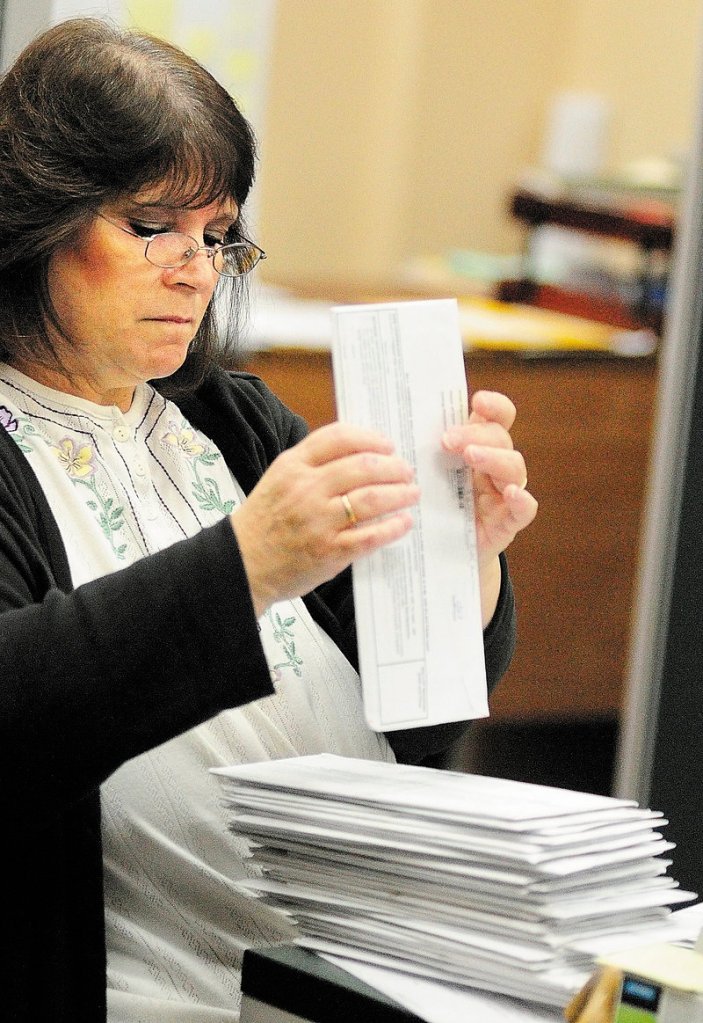 Martha Burns stacks and date-stamps a stack of absentee ballots that arrived by mail at the Augusta City Clerk’s Office on Thursday morning.