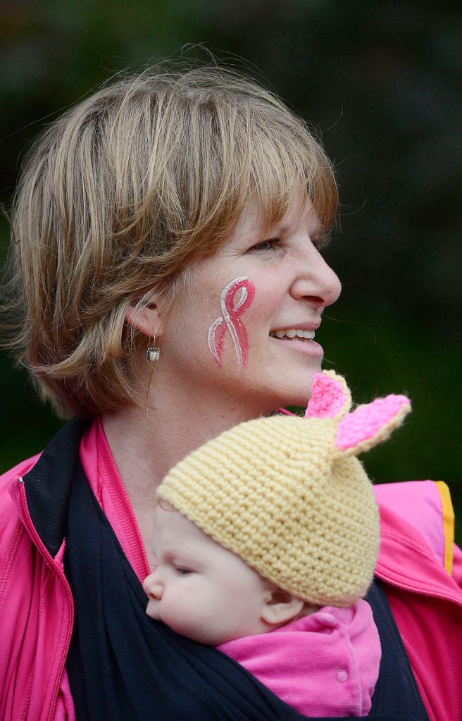 Cristin Doughty of Saco, with a pink ribbon painted on her face, holds her daughter Ava, 3 months, before the start of the Making Strides walk Sunday in Portland.