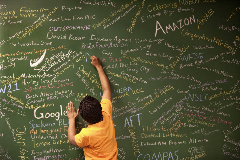 Sylvia Rolle, social-media director for Washington United for Marriage, writes the names of a few more supporters – business, labor, faith and other organizations – on the endorsement wall at the Seattle, Wash., campaign headquarters.