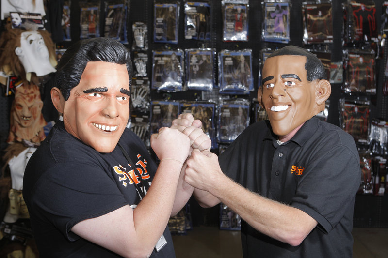 Jeremy Davis and Scott Stevens, employees at Spirit Halloween in South Portland, model masks of Mitt Romney and President Obama. Nationally, Obama was outselling Romney as of last week, says the chain, which claims that sales of such masks have been a successful indicator of presidential preference since 1996.